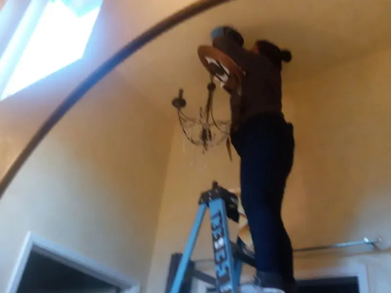 Electrician installing a chandelier in a Vermillion residence